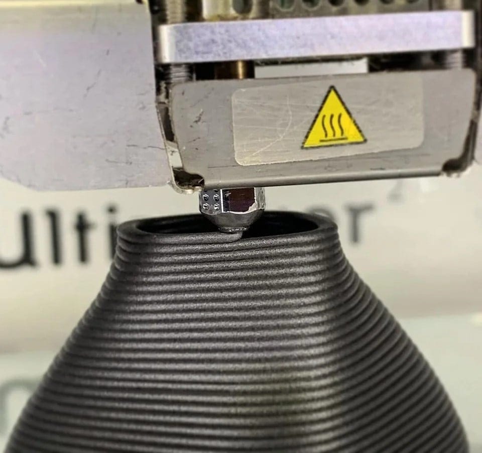 Nozzle depositing a bead onto the previous layers of a printed part