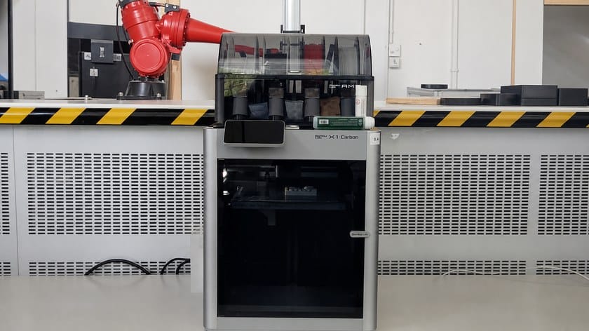 A Bambu Lab X1 Carbon 3D printer with its AMS filament unit on top