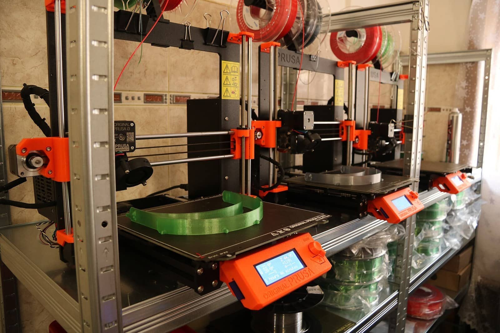 A row of Original Prusa i3 MK3S printers printing face shield frames